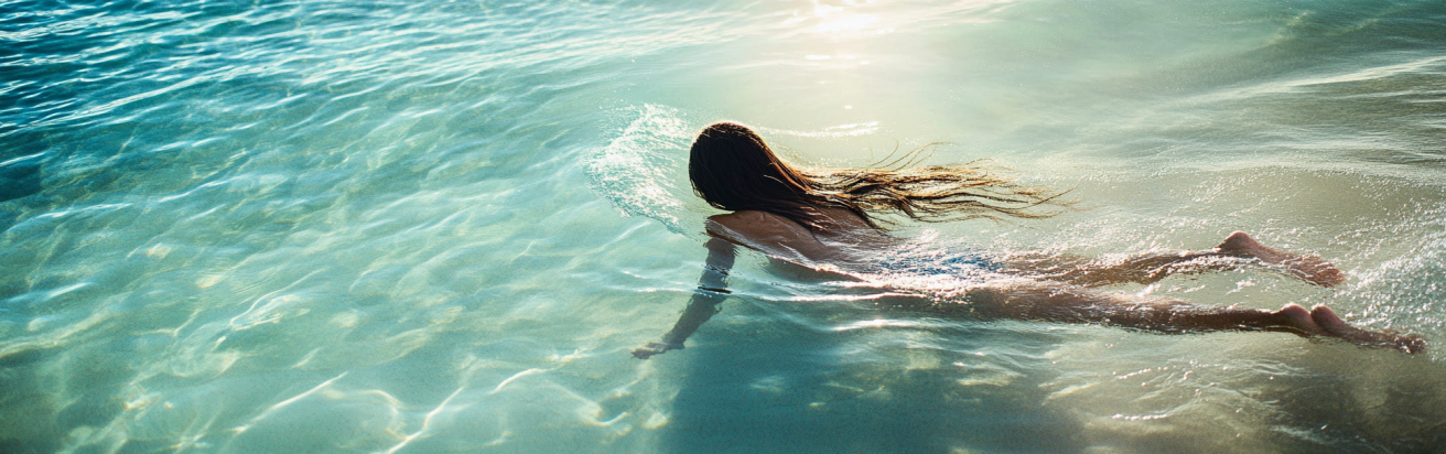 Can Salt Water Damage Your Hair Extensions? 1 Seamlessly blended hair extensions on a woman swimming in clear ocean water.