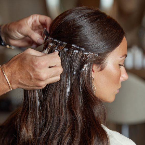Top 35 Hair Extension Hairstyles for Every Occasion 5 A detailed view of visible adhesive strips on tape-in hair extensions as they are applied to natural hair.